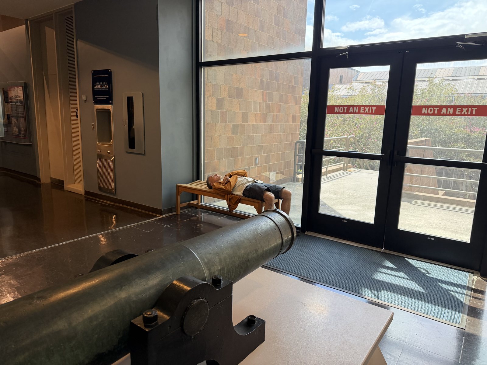 Dad, horizontal on a museum bench, waiting for Travis to finish with the firearms. The cannon is keeping him company.