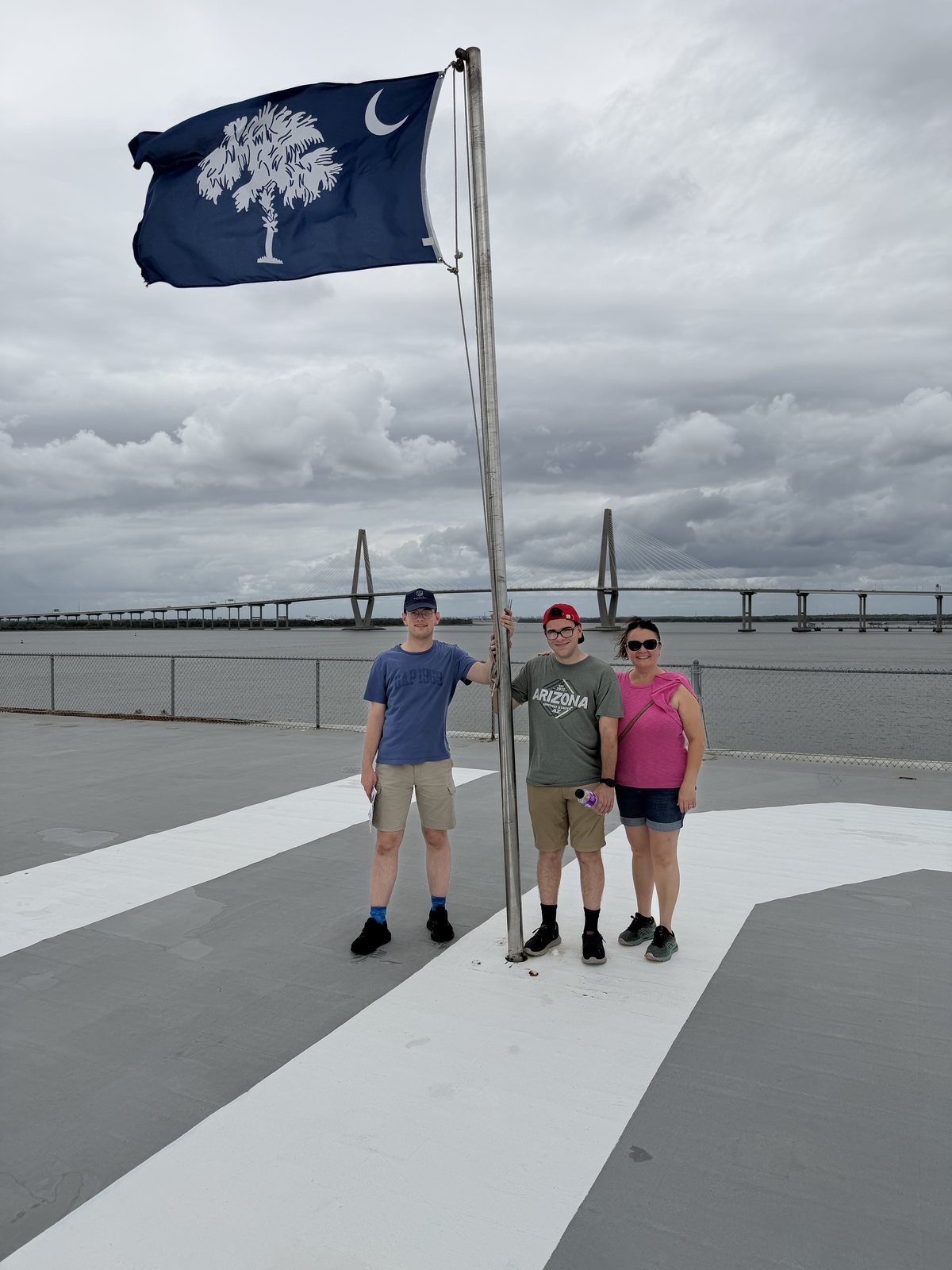 The family on the flight deck — the South Carolina flag above, the Ravenel Bridge behind. Nobody got blown off.